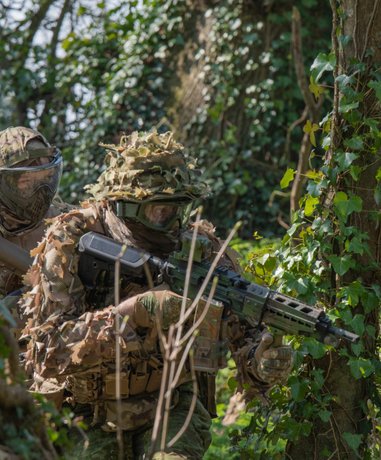 Airsoft player aiming replica weapon in tactical gear
