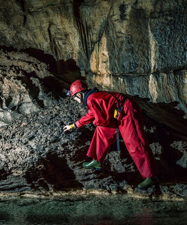 Caver navigating a narrow cave passage