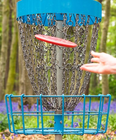Disc golf player aiming at basket in park