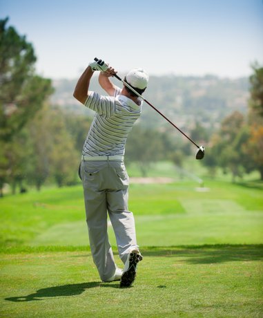 Golfer swinging club on a sunny day