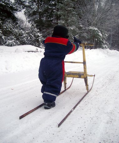 Person kick sledging on snowy track