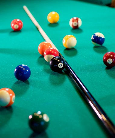 Pool player aiming shot on billiard table