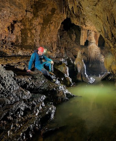 Potholer in cave with headlamp