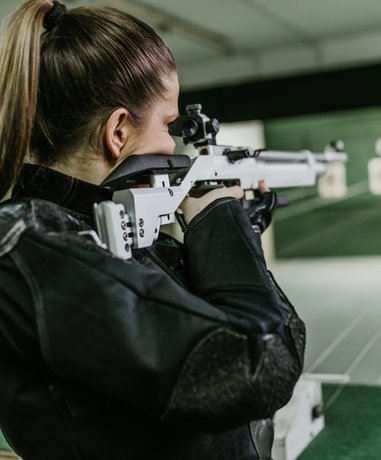 Target shooter aiming rifle at range