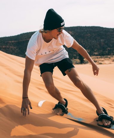 Sand boarder sliding down a dune