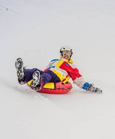 Snow tuber sliding down a snowy hill